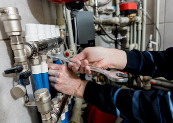 Heating engineer installing modern heating system in boiler room.