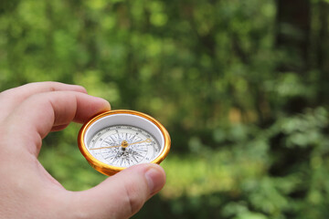 Old classic navigation compass in hand on natural background as symbol of tourism with compass,...