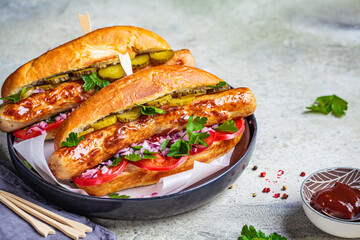 Homemade hot dog with sausage, vegetables and spicy sauce, gray background.