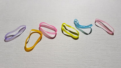 Set of small multi-colored elastic bands for hair on a white table.