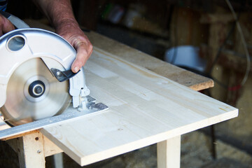 a worker using a circular saw works with wood in a carpenter's workshop
