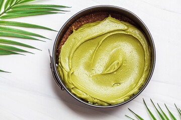 Cooking raw vegan matcha cheesecake on white background.