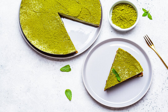 Flat lay of raw vegan matcha cheesecake, white background, top view.