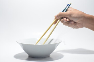 Hand using chop stick against white bowl on isolated white background