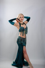 Young beautiful exotic eastern women performs belly dance in ethnic green dress. Isolated on white background. Studio shot