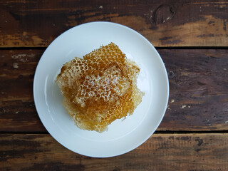 Fresh honeycombs on a plate on a table against a brick wall background