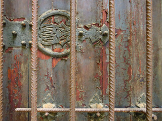 Antique metal ornamental detail on rusty wrought iron wall and grilles. Rusty painted old ornate decorative wrought metal grill in dilapidated state. Background and textures. Old metal grill.