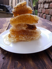 Fresh honeycombs on a plate on a table against a brick wall background