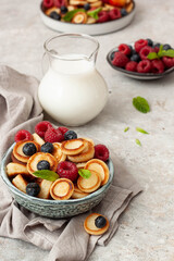 Bowl with mini pancake cereal with raspberries, mint and blueberries.Tasty breakfast