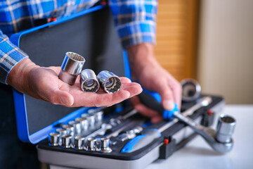 Metal box with a set of keys. A locksmith in a checked shirt holds a key attachment in his hand.