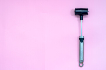 Iron Hammer for beating meat on a pink background. 