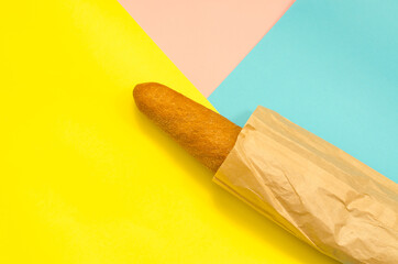 Rye baguette in a paper bag. Bread in a bag on a colorful background. Bakery products.