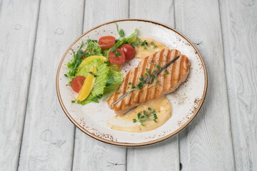 One piece of baked salmon grilled pepper lemon and salt on a white plate