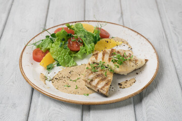 One piece of baked salmon grilled pepper lemon and salt on a white plate