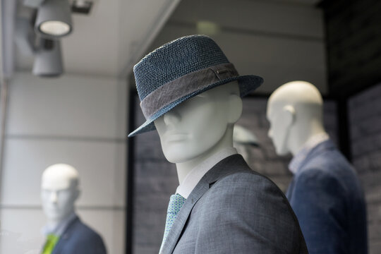 Closeup of grey classic suit for men on manequin with hat in a fashion store showroom