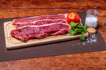 Raw meat. Special fillet steaks with green seasoning and coarse salt on cutting board on the table.