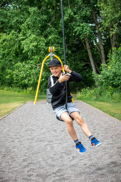 Sporty child smiling riding a zip-line at an playground in a public park.