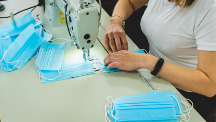 Woman sew the facial medical at sewing machine. Coronavirus pandemia.