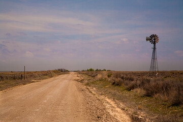Pan Handle, Oklahoma; a gravel county road and a working windmill in the Oklahoma panhandle, about...