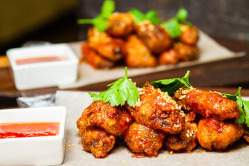 Sesame fried chicken wings with sauce and parsley. Close-up, selective focus