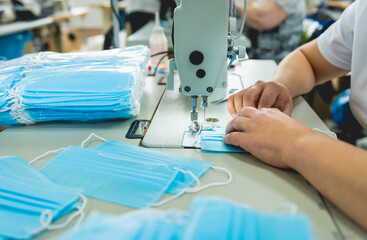 Woman sew the facial medical at sewing machine. Coronavirus pandemia.