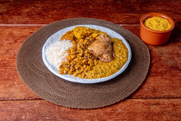 Delicious Caruru. Traditional Afro-Brazilian dish made with okra and dried shrimp, accompanied by vatapa, beans, rice, chicken and farofa. On a wooden table.