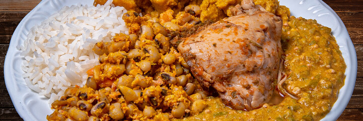 Delicious Caruru. Traditional Afro-Brazilian dish made with okra and dried shrimp, accompanied by vatapa, beans, rice, chicken and farofa. On a wooden table.