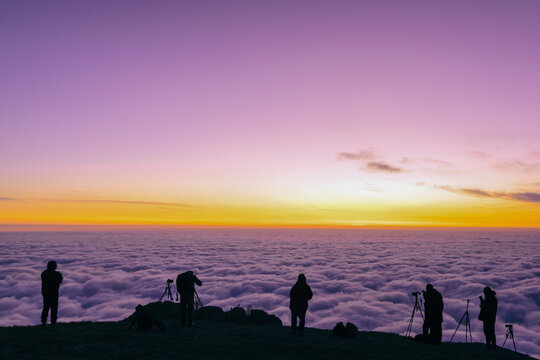 tourists photographers stand on the edge of the mountain and take pictures of the sunrise
