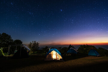 Glowing camping tent on the mountain under a beautiful starry sky at night, Travel lifestyle © Kittiphan