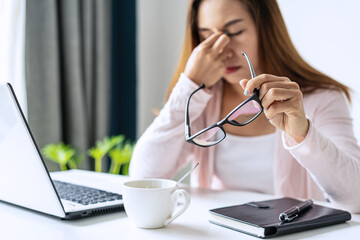 Tired and stressed young asian woman feel pain eyestrain and rubbing her eyes and take off her...