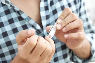 person cutting his nail with nail cutter