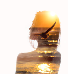 Double exposure portrait of woman and flying bird in sunset reflecting in ocean. Concept of human...