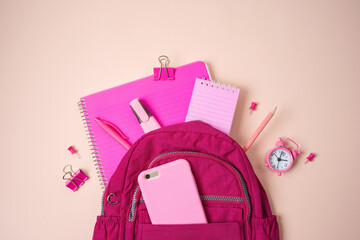 Back to school concept with bag backpack, blank notebook and school supplies on pink background....