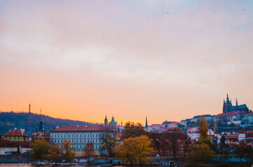 Fototapeta na wymiar Dramatic sundown with a panoramic view of the other side of Prague in the autumn and a gradient of orange to pink colors in the cloudy sky.