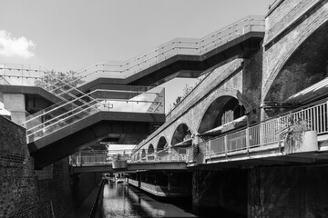 Fototapeta na wymiar Former industrial arches along the Rochdale Canal in Manchester with a modernist floating staircase crossing the water and leading to a transport interchange. 