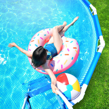 Pool time. Girl has fun in a summer metal frame pool. Cropped.