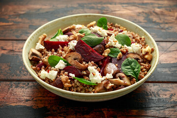 Buckwheat and beetroot salad with mushroom, walnut, spinach and feta cheese on rustic wooden table. healthy diet food