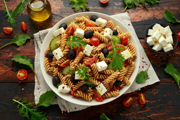 Pasta salad with tomato, black olives, cucumber and feta cheese in white plate. healthy food.