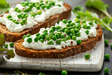 Vegetarian seeded sourdough bread open sandwich with cottage cheese and petit poit peas sprinkled with chilli flakes