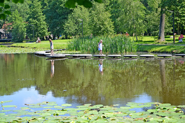 ZELENOGRADSK, RUSSIA - JUNE 25, 2020: Children walk along the path above the water. Tortilin Pond, city park. Kaliningrad region