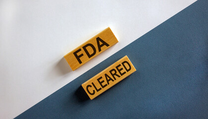 'FDA cleared' words on wooden blocks. Business concept. Beautiful white and blue background.