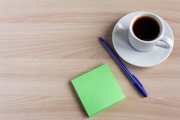 A small Notepad, a pen, and a Cup of coffee on the table.The concept of planning for the day.