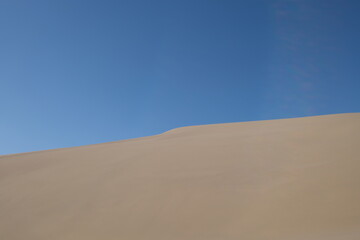 Fototapeta na wymiar sand dune under blue sky. abstract and simplicity. At Dunhuang, Gansu province, China