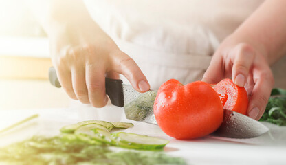 Chef slicing vegetables and tomato on the table in restaurant. Process of cutting and preparation food in kitchen.
