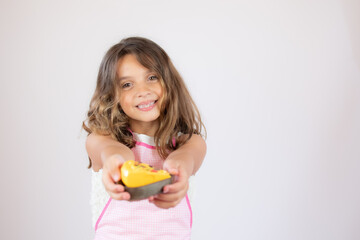 Pretty little girl with a apron on and showing a piece of cake