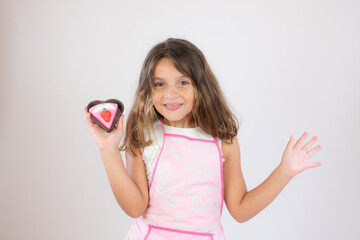 Pretty little girl with a apron on and eating a piece of cake