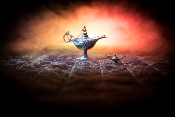 Lamp of wishes concept. Antique Aladdin arabian nights genie style oil lamp with soft light white smoke, Dark background.