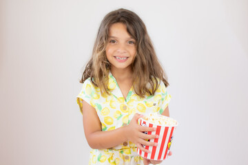 Portrait of a pretty girl with yellow shirt with popcorn in hand