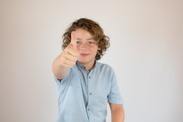 Boy with blue shirt smiling and finger up