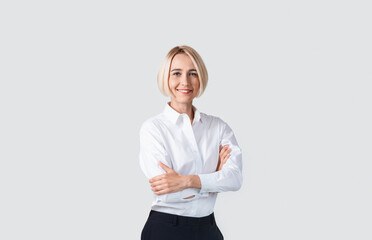 Beautiful businesswoman in formalwear standing with crossed arms on light background